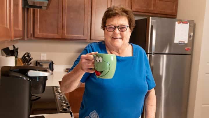 Senior woman holding a novelty dinosaur coffee mug