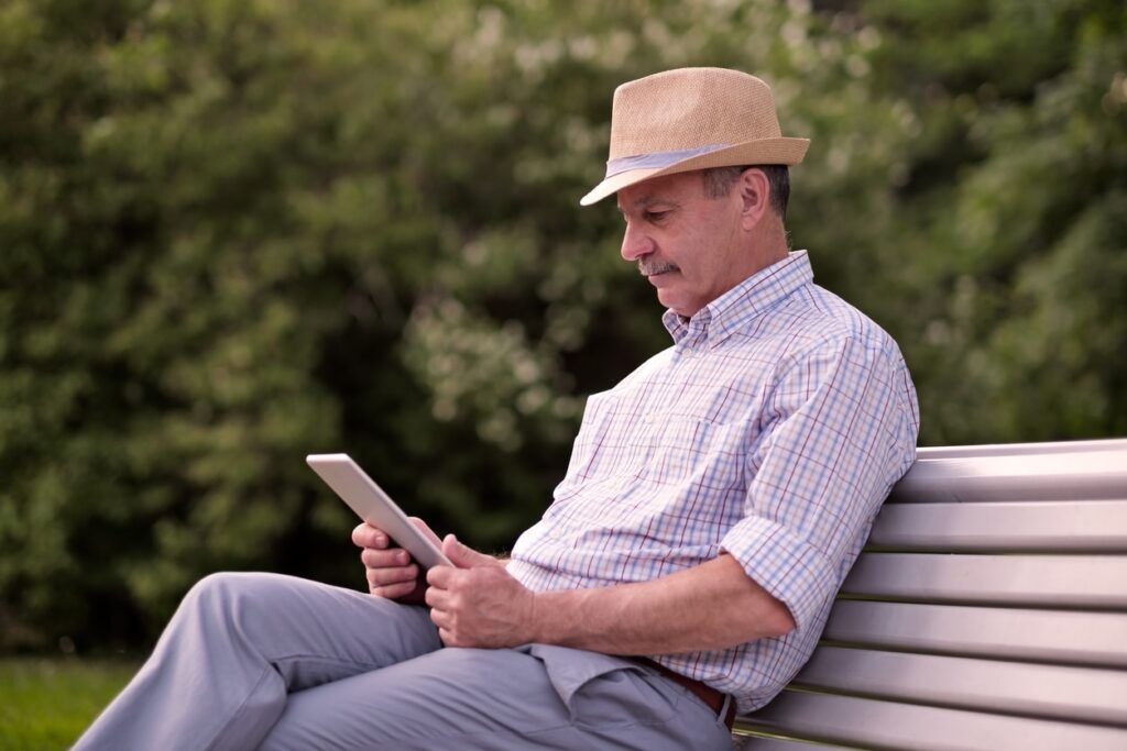 Hispanic senior man in summer hat researching senior living