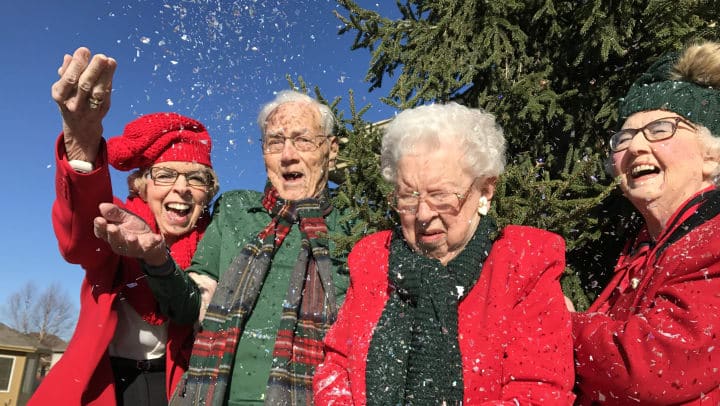 group of seniors taking a selfie outdoors in the snow wearing holiday apparel