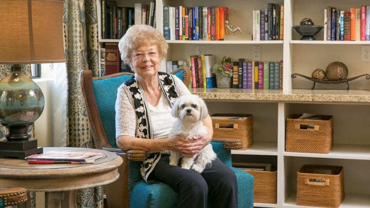 Senior woman with small dog in her lap at an assisted living facility