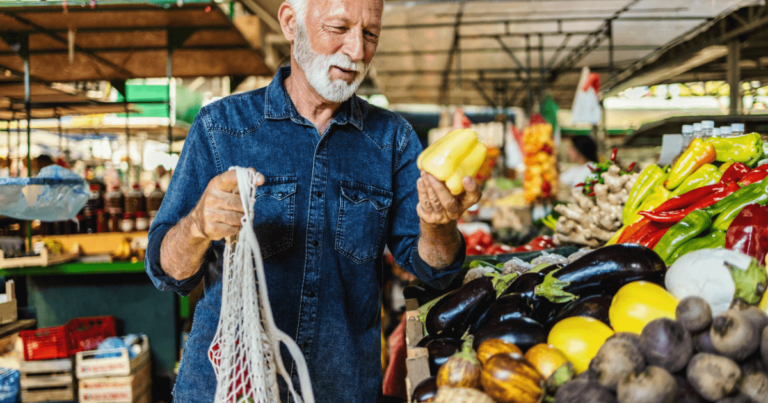 Older man at the market picking out produce for dining options