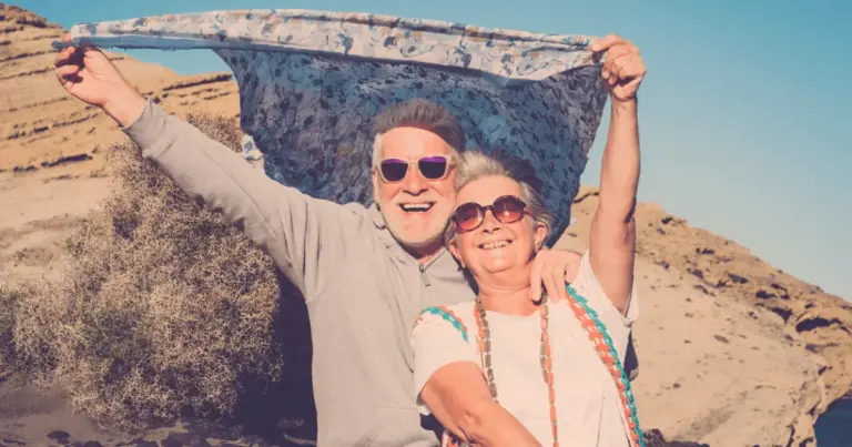 Senior couple enjoying theirselves outdoors with mountains and holding a banner during retirement