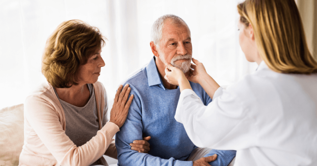 Female physician with couple giving older male a checkup