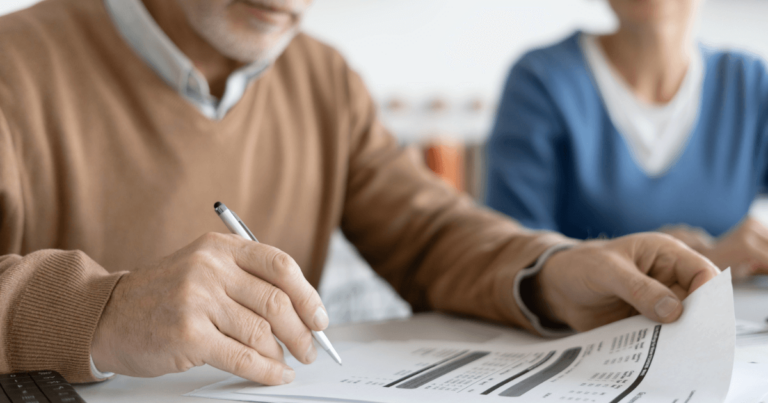 Close up of mans hand writing and reviewing funding sources for senior care.