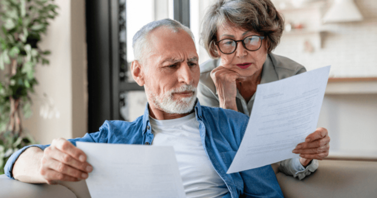 Senior man and woman looking at documents and reviewing their senior living care options.