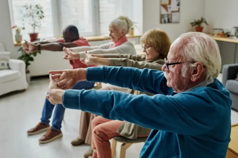 A side view of seniors doing chair yoga and arm exercises in the morning.