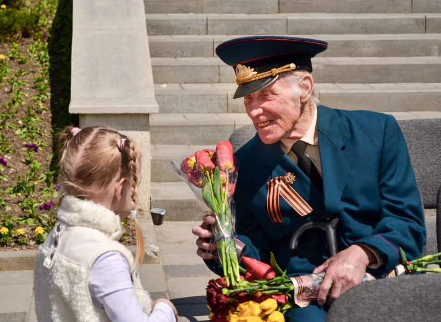 A little girl gives her veteran grandfather some flowers to honor him for Memorial Day.